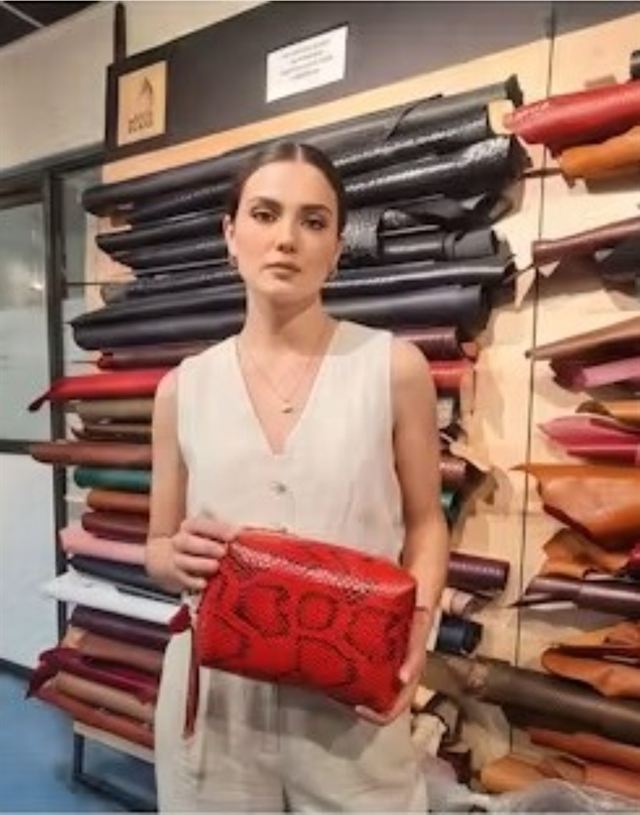 Neceser de cuero frente a los rollos de cuero del taller